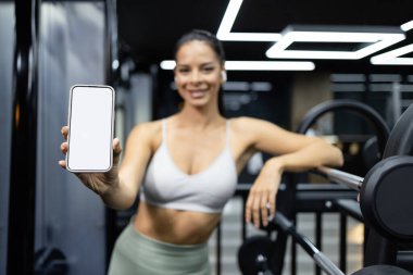 Akıllı telefon beyaz görüntüsü gösteren profesyonel fitness eğitmeni.