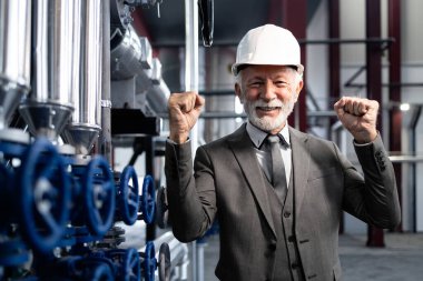 Sert şapkalı deneyimli fabrika müdürü proje başarısı için tezahürat yapıyor..