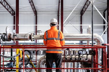 Borular ve makinelerle büyük bir endüstriyel rafineride çalışan işçiler