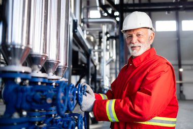 Modern endüstriyel bir ortamda çalışan kıdemli mühendis kontrol vanalarını çeviriyor.