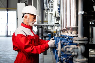 Üretim tesisinde sabit şapka ve üniforma giyen deneyimli bir işçi.