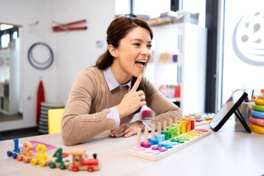 Klinikteki odaklı konuşma terapisi sırasında bir çocuğa ayna ve oyuncaklar kullanarak konuşma terapisi yaptığını gösteren bir konuşma terapisti.