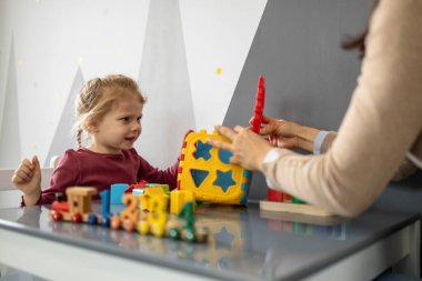 Anaokulu öğretmeninin küçük bir çocukla etkileşimi, eğitim amaçlı oyun zamanını bir şekil ayırıcı ve geliştirme oyuncakları ile yönlendirmesi, destekleyici bir ortamda öğrenme ve bilişsel becerileri geliştirmesi