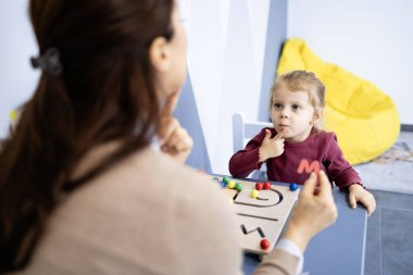 Konuşma patologu, eğitimsel oyunlar ve iletişim becerilerini geliştirmek için bir terapi oturumunda konuşma ve konuşma geliştirme üzerine çalışan küçük bir çocukla birlikte çalışıyor.