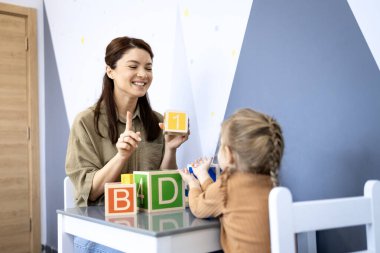 Konuşma terapisti, eğlenceli bir oturum sırasında renkli eğitim engellerini kullanarak bilişsel becerileri, erken gelişimi ve iletişimi geliştirmek için gelişim eğitimine yardımcı oluyor.