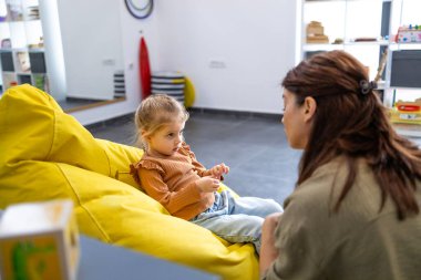 Çocuk psikoloğu, küçük bir kızla rahat bir ortamda ilişki kuruyor. Duygusal ve psikolojik gelişim ve refah için terapi ve rehberlik sunuyor.