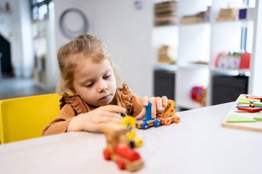 Tahta bloklara odaklanan genç kız, oyun tabanlı bir sınıfta sayım ve sayısal tanıma yaparken iyi motor beceriler ve problem çözme yetenekleri geliştiriyor.