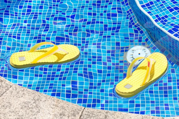 Paar van flip flops in een blauwe zwembad — Stockfoto