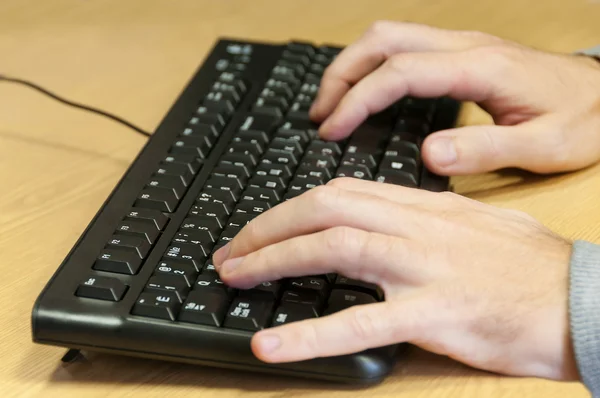 Mani di uomo digitando su una tastiera — Foto Stock