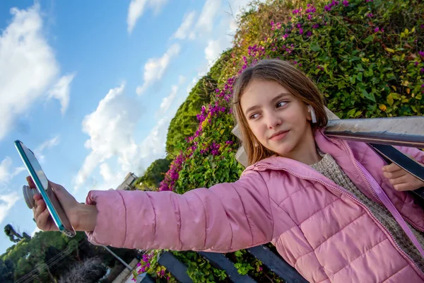 a teenage girl in a purple jacket takes a picture of herself (selfie) or shows a video link of her smartphone