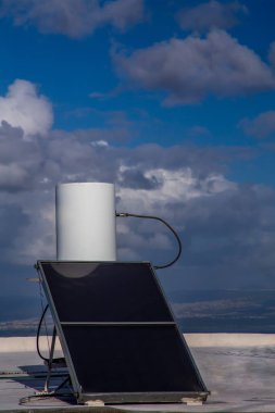solar rooftop boiler on a sunny day against the background of the sky with clouds clipart