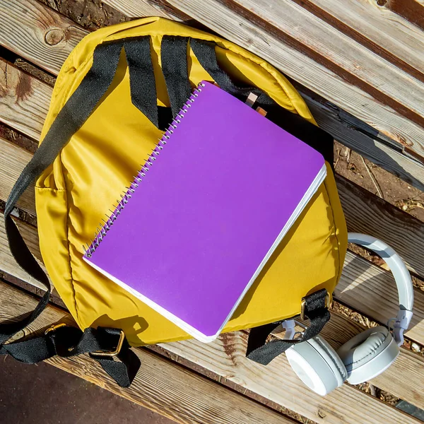 Желтый Рюкзак Фиолетовый Школьный Блокнот Белые Наушники Лежат Деревянной Скамейке — стоковое фото