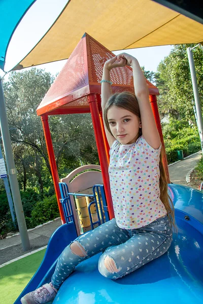 Güzel duygusal genç kız güneşli bir günde çocukların oyun parkında geriliyor.