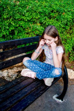 Genç kız şehir bankında oturmuş meditasyon yapıyor.