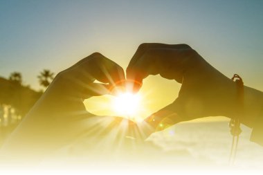 Gün batımının üstünde elleri olan çocuksu bir kalp şekli.