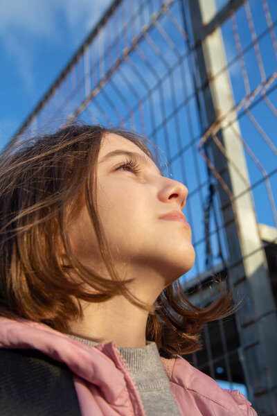 Beautiful, natural teen girl stretches her face towards the sun on a bright sunny day