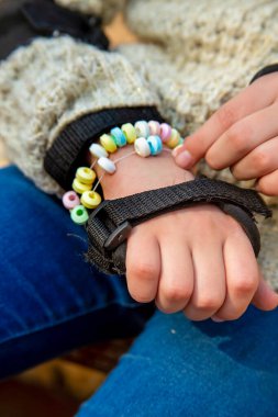 Koruyucu aksesuarlı kızın elleri parmaklarıyla yenilebilir bir bileziğin renkli şekerlemelerini tutuyor.