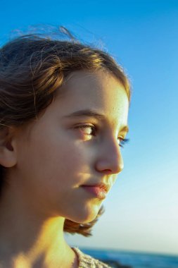 Güzel ve tatlı doğal genç kız gün batımında güneşe bakıyor.