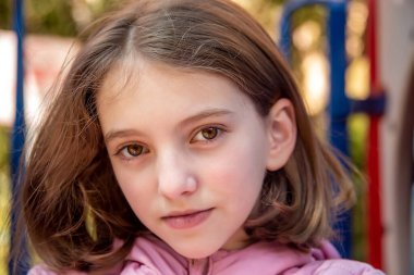 Güneşli bir günde parkta pembe ceketli güzel, doğal bir genç kızın portresi.