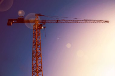 Açık mavi arkaplanda büyük sarı bir vinç var.
