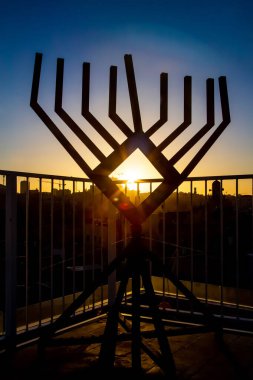 Ev yapımı Hanuka menorası ve ortasındaki güneş günbatımının arka planına karşı.