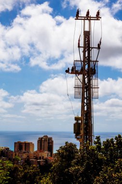 Mavi gökyüzündeki elektrik direğinde yüksek voltajlı elektrik hattı