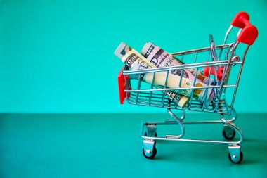 konsept - Alışveriş Arabası Tramvayı 'nda yeşil arka planda kıvrılmış dolar banknotları