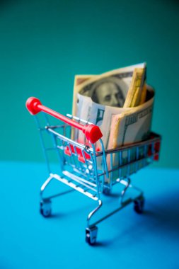 konsept - kıvrımlı dolar banknotları yeşil arka planda alışveriş arabasında yatıyor