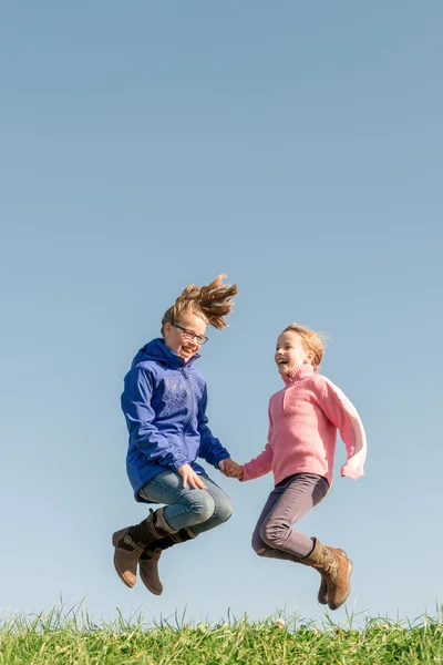 Jumping girls on green grass — Stock Photo, Image