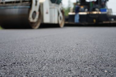 Görüntü asfalt yol yapımında bulanıklaşıyor. Ağır makinelerle.