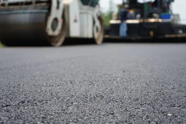 Görüntü asfalt yol yapımında bulanıklaşıyor. Ağır makinelerle.