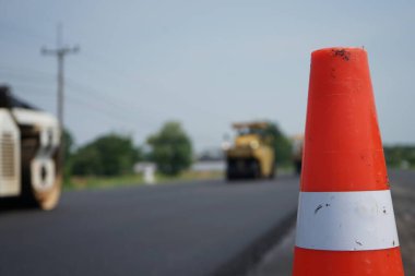 Asfalt asfaltlama bulanıklığı Önünde kırmızı bir lastik koni var.