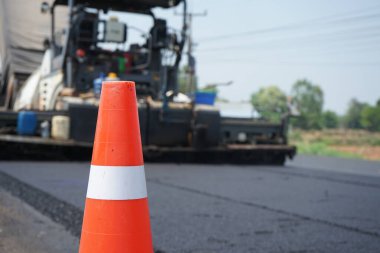 Asfalt asfaltlama bulanıklığı Önünde kırmızı bir lastik koni var.