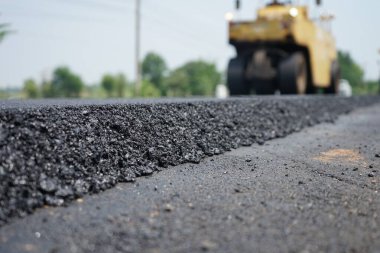 Görüntü asfalt yol yapımında bulanıklaşıyor. Ağır makinelerle.