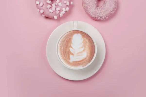 粉红背景的扁平的甜甜圈和一杯咖啡 — 图库照片