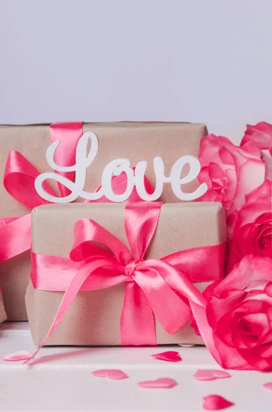 La palabra amor en letras blancas en cajas de regalo con cintas rosas. Concepto de amor, San Valentín —  Fotos de Stock