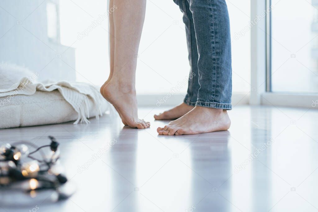 Close-up of legs of the kissing couple on wooden floor