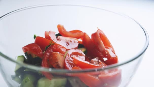 Salat de tomate tempero com uma pitada de sal sobre legumes picados em uma tigela de vidro — Vídeo de Stock