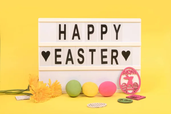 Happy Easter letters and easter eggs on bright yellow background