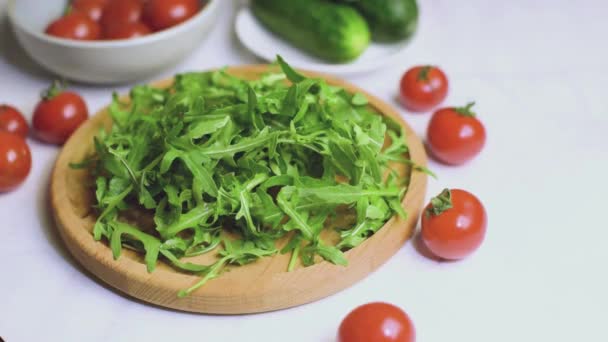 Hojas frescas de rúcula orgánica que caen sobre un plato de madera para cocinar ensalada. — Vídeos de Stock