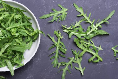 Taze roka yaprakları karanlık masada kasede. Taze vejetaryen gıda konsepti, yakın plan, düz yatak.