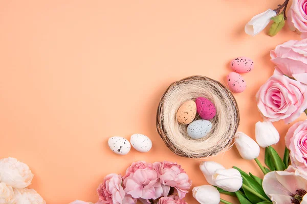 Décorations colorées avec nid d'œufs de Pâques avec des fleurs de printemps sur fond orange. espace de copie, vue du dessus — Photo