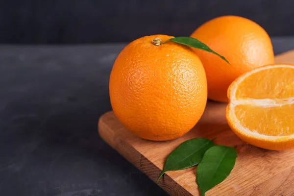 Fresh orange fruit with leaves on wooden table — Stock Photo, Image