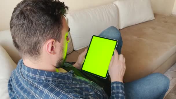 Парень, использующий планшет с сенсорным экраном для серфинга он-лайн и чтения электронной почты дома — стоковое видео