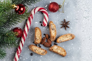 Geleneksel İtalyan bisküvisi ya da bademli Cantuccini kurabiyeleri, badem ve çikolatalı gri arka planda çikolata ve ceviz, bir Noel ağacı. Noel pastası konsepti.