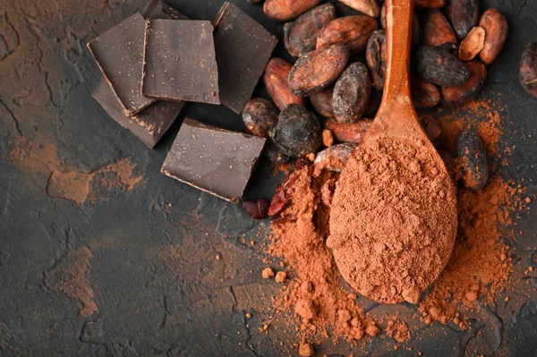 Pieces of dark chocolate, cocoa powder and cocoa beans, culinary background. Copy space