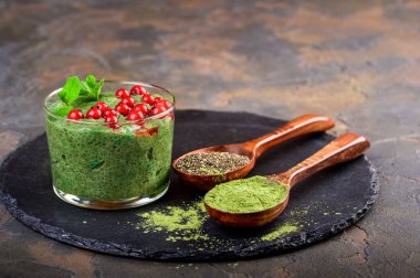 Kibrit yeşil çay chia tohumu pudingi, taze naneli tatlı, böğürtlen ve siyah arkaplanda hindistan cevizi. Sağlıklı kahvaltı.