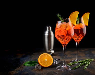Şarap kadehi soğuk Aperol sprey kokteyli portakal ve biberiye dilimleri ile süslenmiş bir şarap kadehinde servis edilir. Siyah arka plan. Boşluğu kopyala