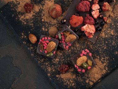 Kurutulmuş çilekli ev yapımı çikolata: ahududu, çilek ve fındık. Koyu arkaplan