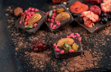 Kurutulmuş çilekli ev yapımı çikolata: ahududu, çilek ve fındık. Koyu arkaplan